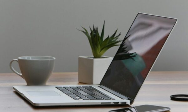 Free Minimalist home office desk with laptop, smartphone, and plant for a modern work environment. Stock Photo