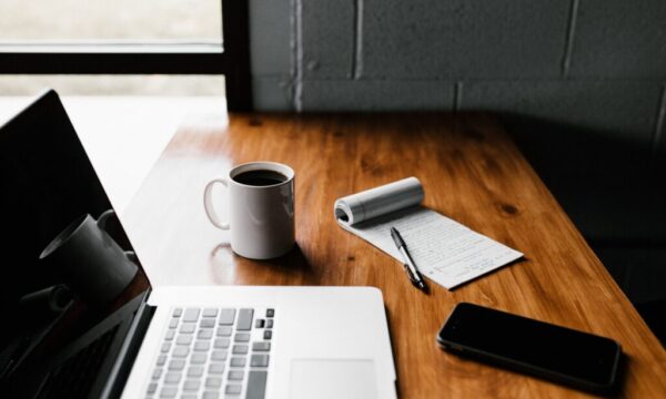 MacBook Pro, white ceramic mug,and black smartphone on table