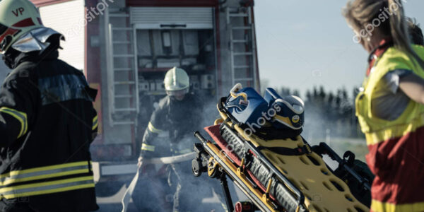 On the Car Crash Traffic Accident Scene: Paramedics and Firefighters Rescue Injured Victims Trapped in the Vehicle. Medics Use Stretchers, Perform First Aid.